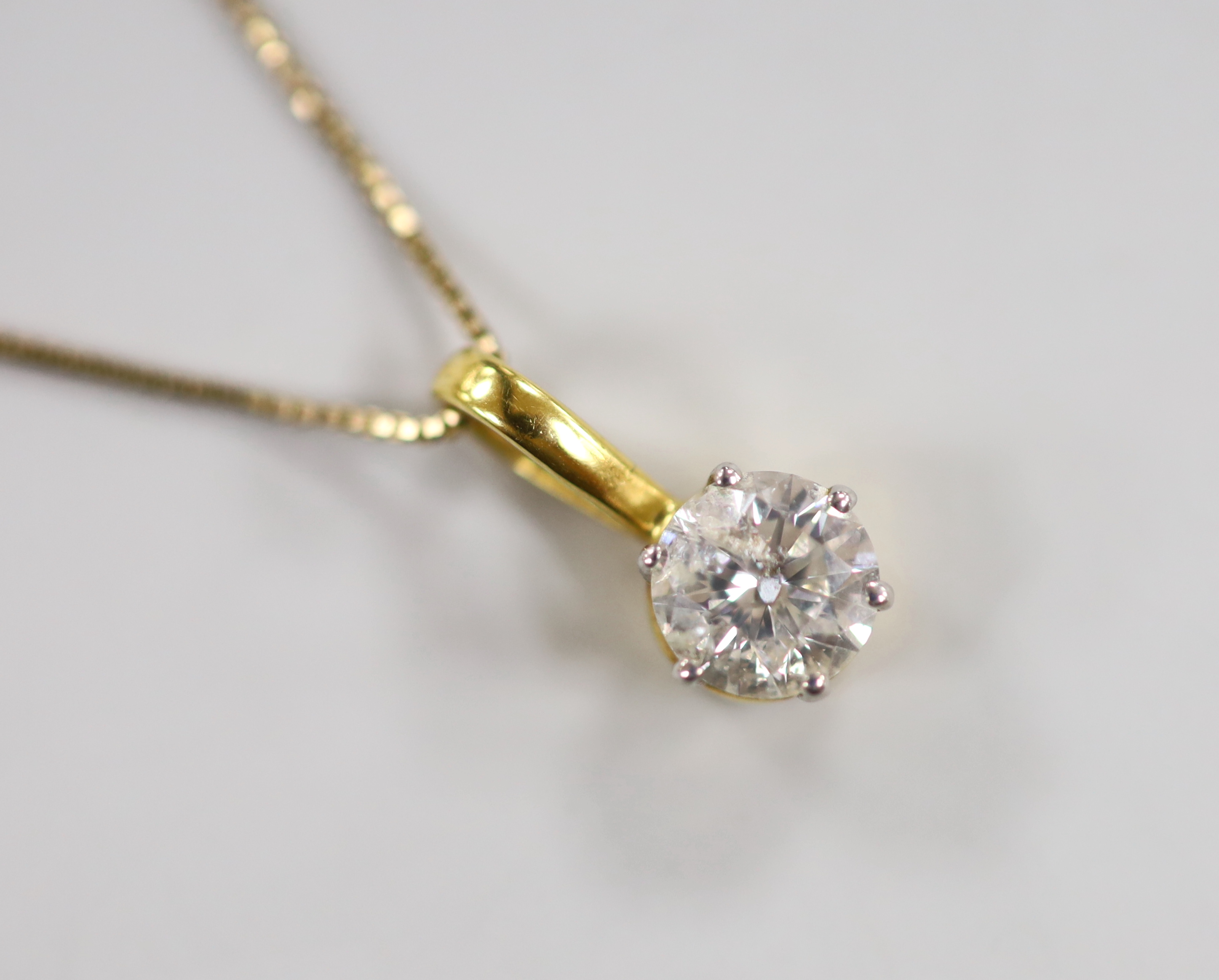 A yellow metal and solitaire diamond set pendant, 15mm, on a 9ct chain, 42cm, gross weight 2.7 grams.